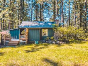 a small blue house in the middle of a yard at Bridlewood Cabin - Meredith Lodging in Welches