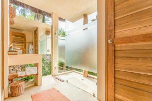 a pivot door in a bathroom with a glass shower at Ahau Tulum - Beachfront Hotel in Tulum +121 photos