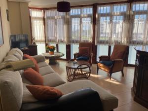 Piso grande en LLANES con garaje في يانس: غرفة معيشة مع أريكة وكراسي ونوافذ