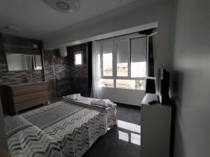 a bedroom with a bed and a television and a window at Piley apartamento en vila-real in Villareal