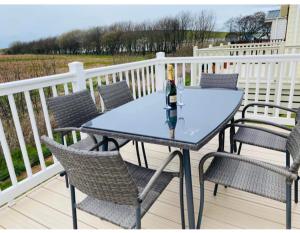una mesa con sillas y una botella de vino en la terraza en AJL Rentals en Turnberry