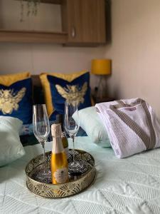 ein Tablett mit einer Flasche Champagner und zwei Gläsern auf dem Bett in der Unterkunft Deluxe 3 bedroom caravan in Haven's Seton Sands Holiday Village,Wifi in Port Seton