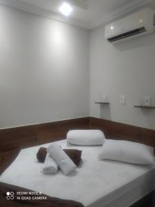 Bett in einem Zimmer mit zwei Kissen darauf in der Unterkunft Pousada Quarto Casal com ar,frigobar, garagem in Aparecida