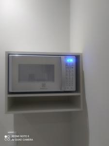 un horno microondas en un estante de la pared en Pousada Quarto Casal com ar,frigobar, garagem, en Aparecida