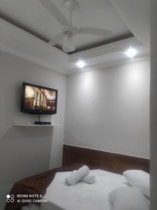 ein Schlafzimmer mit einem Bett und einem TV an der Wand in der Unterkunft Pousada Quarto Casal com ar,frigobar, garagem in Aparecida