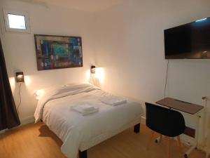 a bedroom with a bed and a desk and a television at Cosy Studio Proche Paris Expo in Vanves