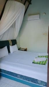 un letto bianco in una stanza con baldacchino di The Pondok a Kuta Lombok