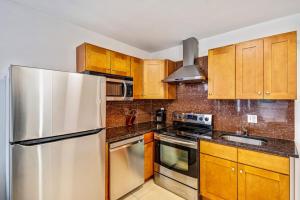 a kitchen with wooden cabinets and a stainless steel refrigerator at Bright stylish &great location 2bd Apartment in Philadelphia