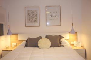 um quarto com uma grande cama branca e 2 almofadas em Apartamentos La Herradura Viñas em Haro