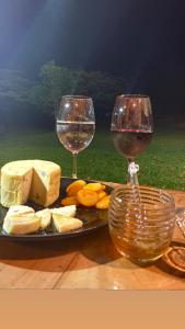 a plate of cheese and two glasses of wine at Pousada Chalés Praia Vermelha in São João Batista do Glória
