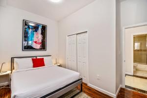 um quarto branco com uma cama com uma almofada vermelha em Escape to Philly and stay in our place! 2BD Apartment em Filadélfia