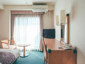 a hotel room with a bedroom with a desk and a bed at Kuretake Inn Okayama in Okayama