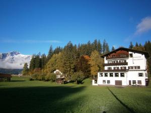 ein großes weißes Haus auf einem Feld mit Bäumen und Bergen in der Unterkunft Pension Waldrast in Ehenbichl