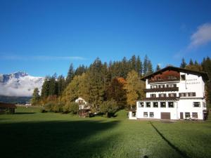 Ehenbichl的住宿－瓦爾德拉斯特旅館，一座大白房子,位于一片树木和山脉的田野中