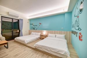 een slaapkamer met 2 bedden en een blauwe muur bij 僑居民宿 in Magong