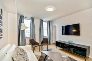 een woonkamer met een witte bank en een flatscreen-tv bij Forget the Hotel and stay in Style in a 2bd Apt in Philadelphia