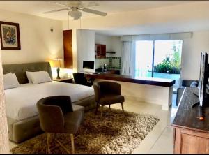 1 dormitorio con 1 cama, escritorio y sillas en Hacienda del Mar Resort Condominio 205, en Cancún