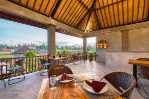 um restaurante com uma mesa e cadeiras numa varanda em Villa Mirah Ubud em Ubud