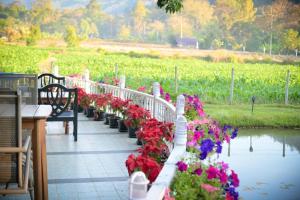 a row of benches with flowers next to a pond at Gumbie House in Fang