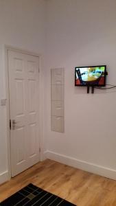Cette chambre est dotée d'une télévision sur un mur avec une porte. dans l'établissement Shepherd's Bush Flats, à Londres