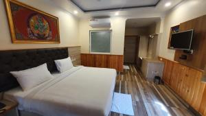 a bedroom with a large bed and a flat screen tv at Nomadic Inn in Dharamshala