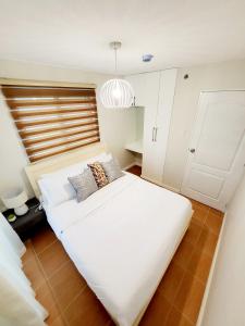 een slaapkamer met een groot wit bed met kussens erop bij Kate's Corner @ One oasis Condo in Cagayan de Oro