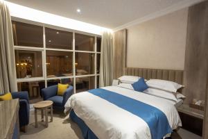 Schlafzimmer mit einem blauen und weißen Bett und Stühlen in der Unterkunft Sweet Light Serviced Apartments in Tabuk