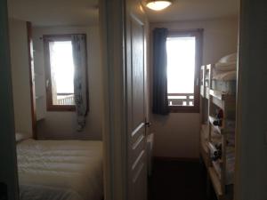 ein Schlafzimmer mit einem Bett und zwei Fenstern in der Unterkunft Lama-Gîte-des-Puys T3 Lamado vue époustouflante sud avec grande terrasse in Super Besse