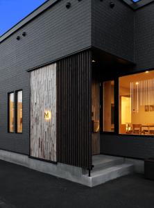 un edificio de ladrillo negro con una gran puerta de cristal en M House, en Furano
