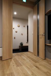 Habitación con pasillo, suelo de madera y TV. en M House, en Furano