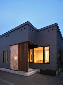 a black brick house with a large window at M House in Furano