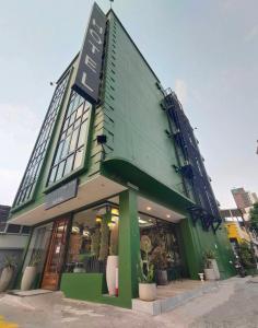 a green building with a sign on the side of it at VIVA LA VIDA HOTEL in Bangkok