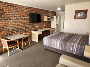 a hotel room with a bed and a desk and a tv at Country Roads Motor Inn Naracoorte in Naracoorte