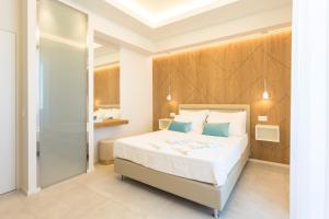 1 dormitorio con 1 cama blanca grande con almohadas azules en Hotel Alexandra - Beach Front -XXL Breakfast & Brunch until 12 30pm, en Misano Adriatico