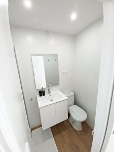 ein weißes Bad mit einem WC und einem Spiegel in der Unterkunft Acogedor y luminoso apartamento muy cerca de la playa con parking gratis y piscina in Calella de Palafrugell