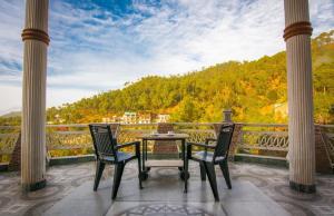 a table and chairs on a balcony with a view at Ram Cottage Chail 3 BHK villa with Lawn & Parking in Chail