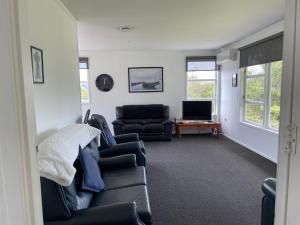 ein Wohnzimmer mit einem Sofa und einem TV in der Unterkunft Superior Cottage - St Enoch and St Elijah Monastery in Kaikohe