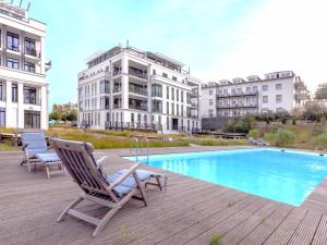 a couple of chairs sitting on a deck next to a pool at Villa Claire - Meerblicksuite "Sunrise Queen" in Ostseebad Sellin