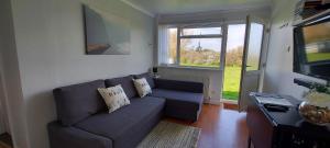 a living room with a blue couch and a window at Rosa Blanca in Sandown