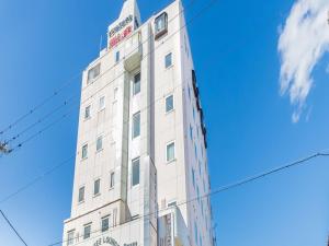 a tall white building against a blue sky at Business Hotel Kawashima in Wakayama
