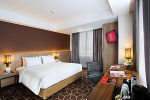 a hotel room with a large bed and a desk at Swiss-Belinn Tunjungan Surabaya in Surabaya