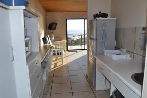 cocina con nevera y vistas al océano en Aan’t See Apartment, en Lambertʼs Bay