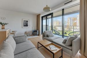 a living room with two couches and a large window at Gdańsk Tarasy Bałtyku Sea Side by Downtown Apartments - Sauna, Gym & Parking in Gdańsk