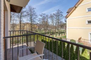 a balcony with two chairs and a view of a yard at Villa Bianca in Pustkowo