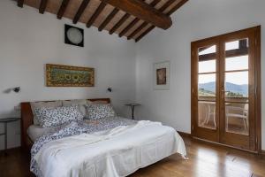 a bedroom with a bed and a large window at Villa Montegemoli - by Bolgheri Holiday in Pomarance