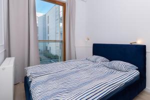 a bed with two pillows in a room with a window at Marine Apartments Nadmorski Dwór in Gdańsk