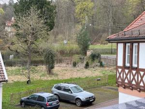 due auto parcheggiate in un parcheggio accanto a una casa di Ferienwohnungen Historische Post a Bad Liebenstein