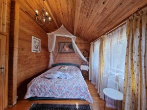 a bedroom with a bed in a wooden cabin at Viesu nams Vecmuiža in Tūja