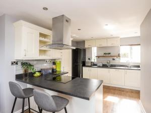 a kitchen with white cabinets and a black counter top at Mor a Mynydd in Caernarfon
