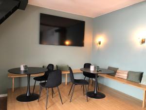 two tables and chairs in a room with a tv at B&B Emma in Geleen